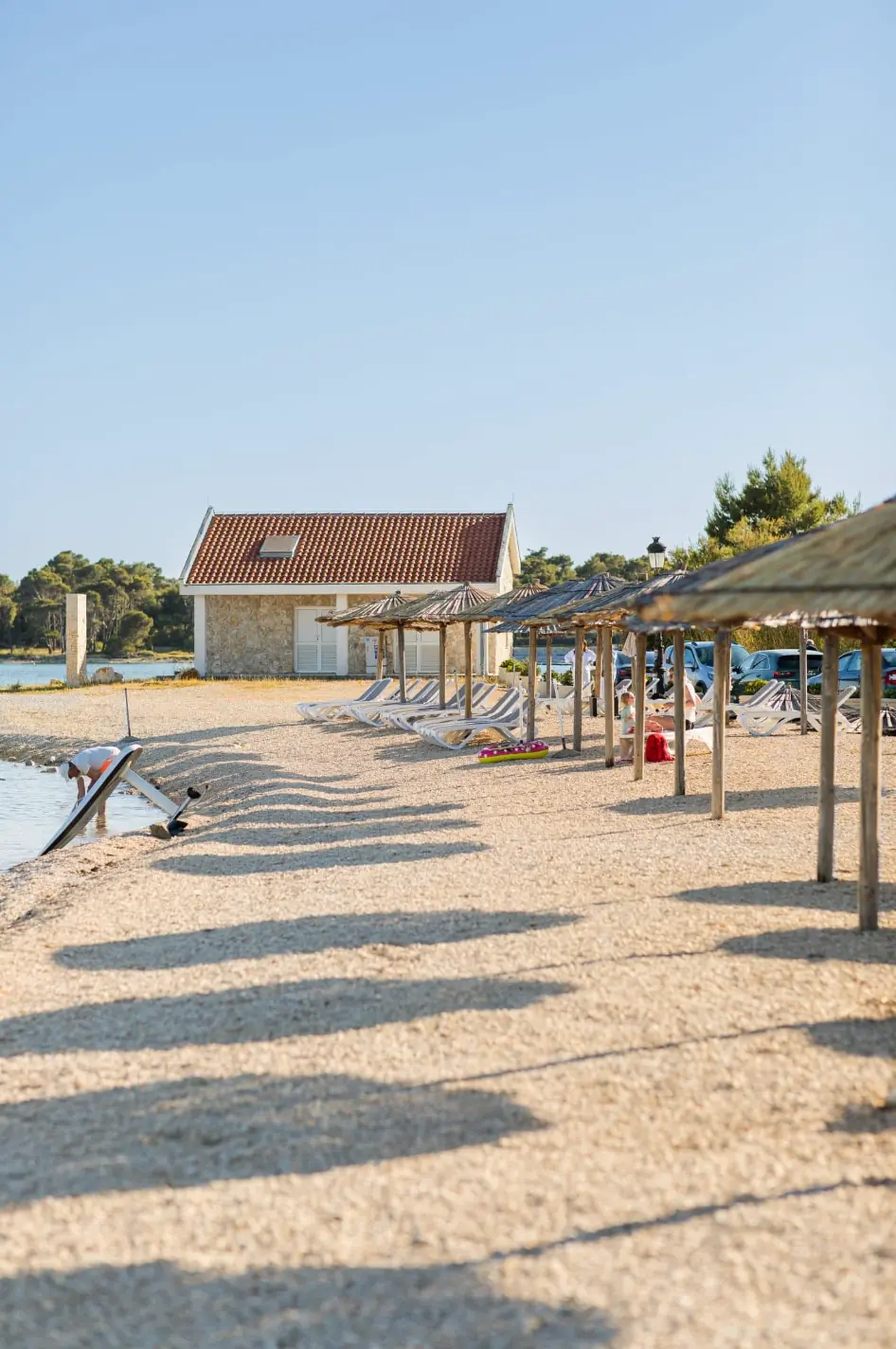 Ruhiger Kiesstrand in Kroatien mit Sonnenschirmen und türkisblauem Meer